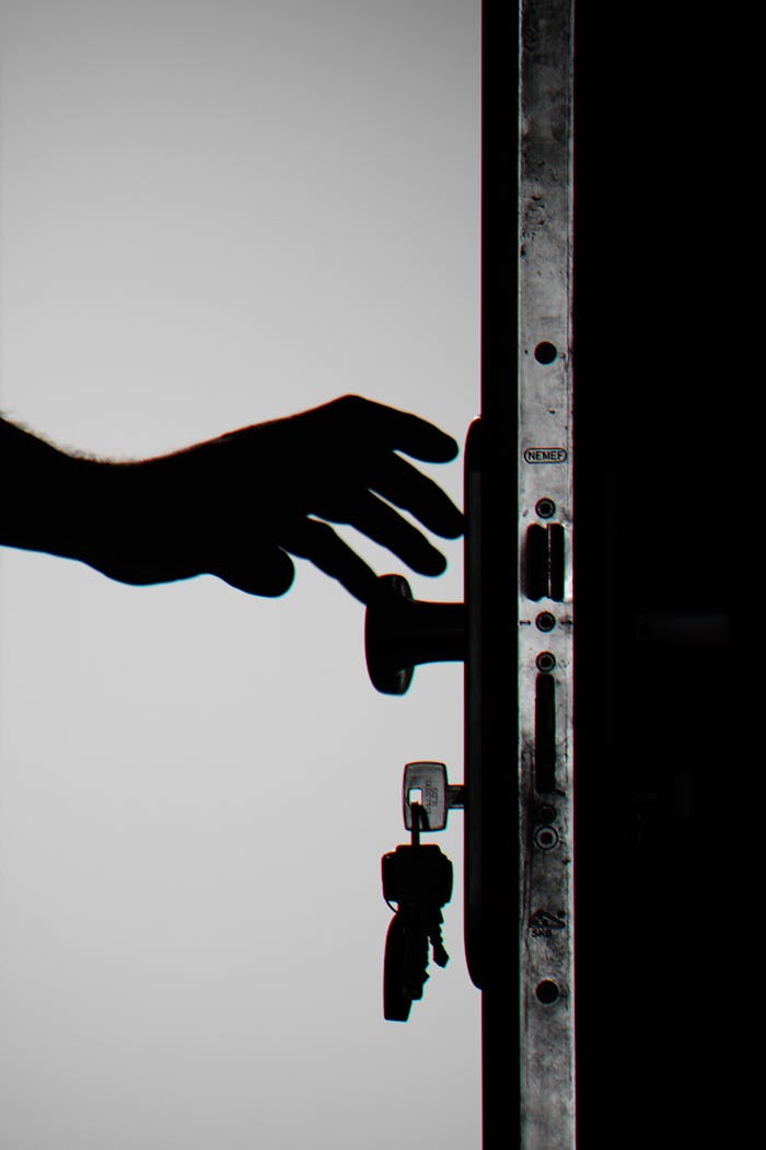 About Silhouette of a hand about to open a door with keys in lock, symbolizing security.